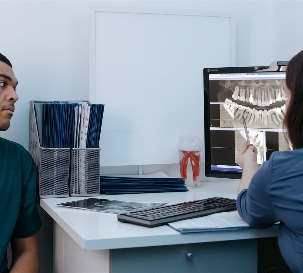 Dentist reviewing dental x-ray with patient to evaluate candidacy for dental implants