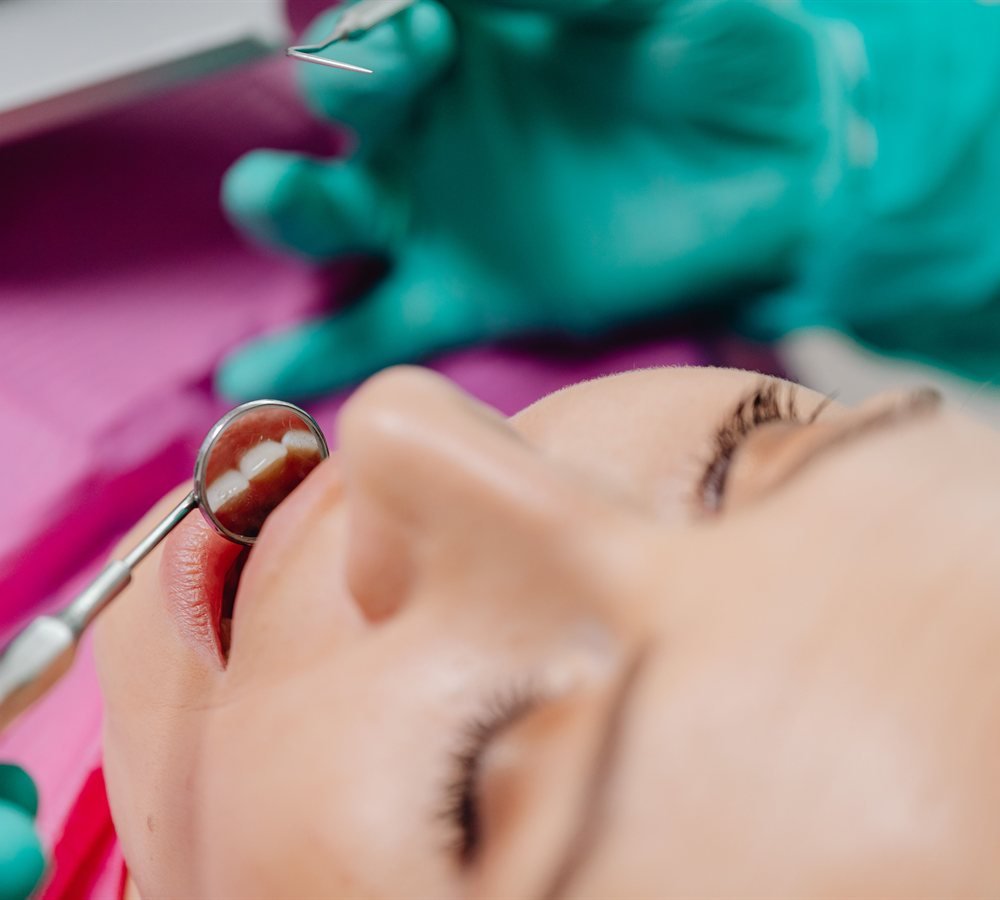 Close-up of periodontist reviewing gum tissue for pinhole surgical technique candidacy